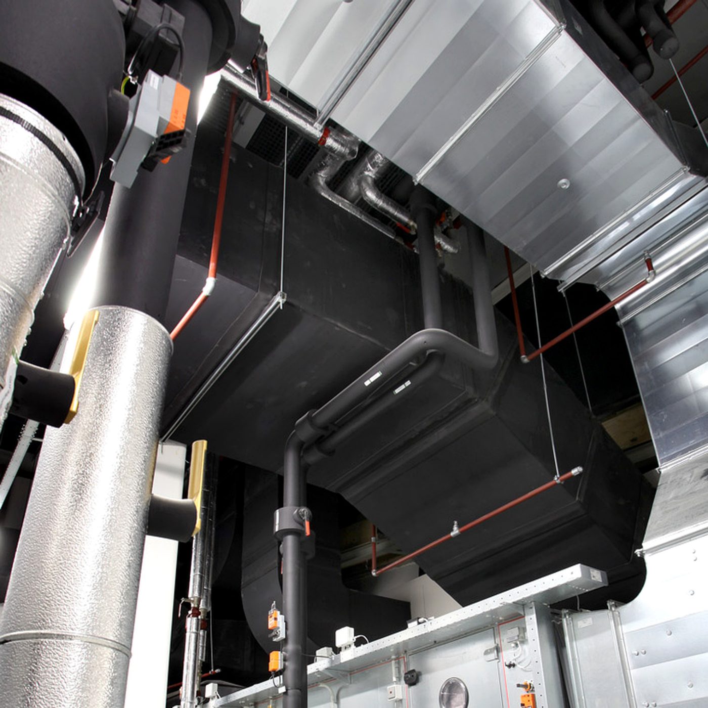 Tubulatură HVAC izolată la o unitate de tratare a aerului, montată pe acoperișul unei clădiri comerciale