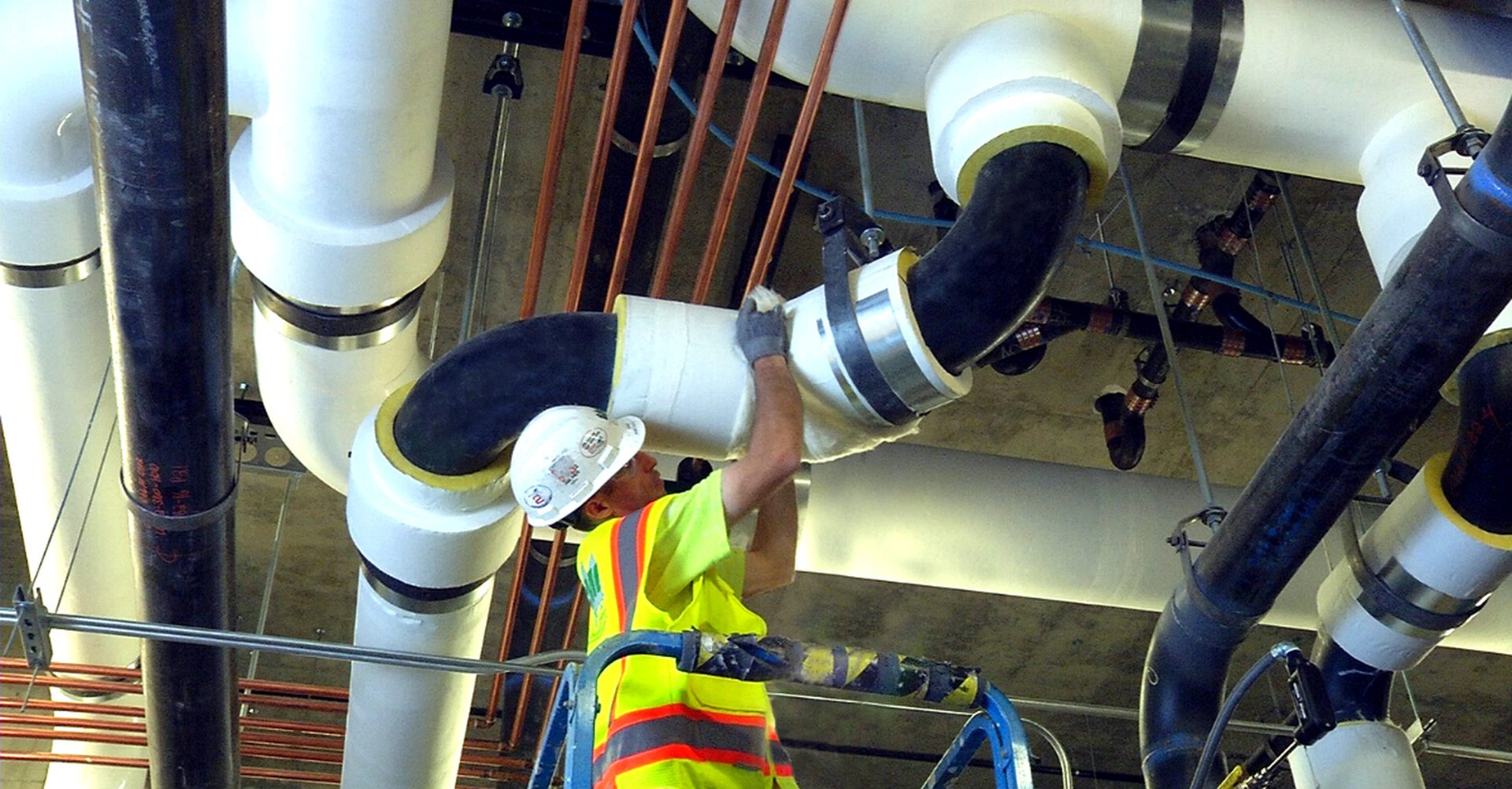 Montaj izolație elastomerică pe conducte HVAC într-o sală tehnică a unei clădiri comerciale